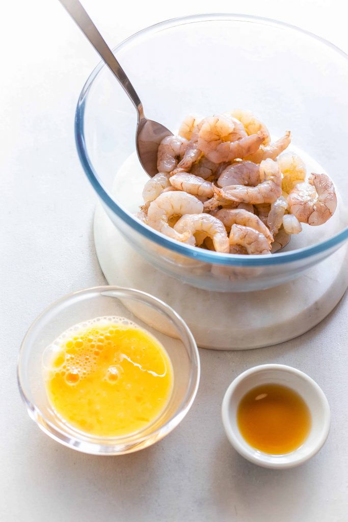 shrimp in a bowl next to eggwash and a dish with fish sauce