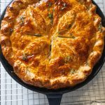 Close-up of the buttery puff pastry crust on top of the skillet chicken pot pie